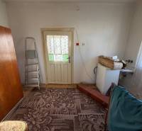 Interior of a family house with a carpet, ladder, and door with a lace curtain.