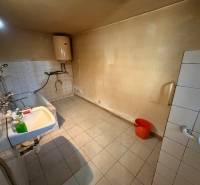 Bathroom in a family house with a bathtub, sink, boiler, and white tiles.