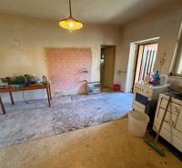 A kitchen in a family house with wallpaper, a stove, and a table on a carpet.