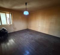 An unfurnished room with a simple lamp, a stove, and a wooden-patterned floor in a family house.
