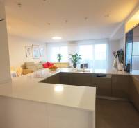A kitchen corner in a 4-room apartment with a countertop, appliances, and a bright living room in the background.