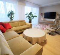 Living room with a beige sofa, red cushions, and a wooden decor floor in a 4-room apartment.
