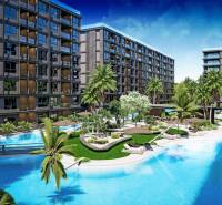 Apartment construction in Pattaya with green areas and a swimming pool among modern buildings.