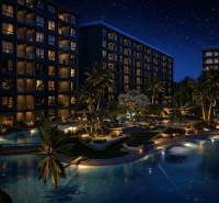 Night construction of apartments in Pattaya with illuminated buildings and a pool.