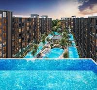 Apartment construction in Pattaya with large pools and palm trees between the buildings.