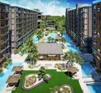 Apartment construction in Pattaya with a swimming pool, palm trees, and relaxation areas in the garden.