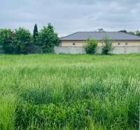 A plot for residential use on Podháj Street in Hviezdoslavov, surrounded by greenery and residential buildings.