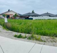 Plots - housing on Podháj Street in Hviezdoslavov, with grassy areas and family houses in the background.