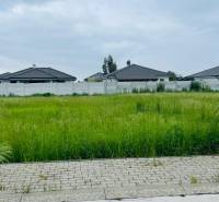 Grass is growing on the plot in Podháj in Hviezdoslavov, the surrounding houses are behind a fence.