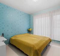 A bedroom with a blue wall, a yellow blanket, and light curtains in a 3-room apartment.