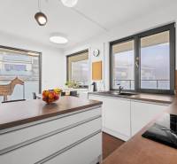 A kitchen in a 3-room apartment with an island, wooden decor, and large windows.