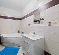 A bathroom in a 3-room apartment with a bathtub, sink, and washing machine.