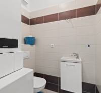 Bathroom with a toilet and sink in a 3-room apartment with elegant tiles.