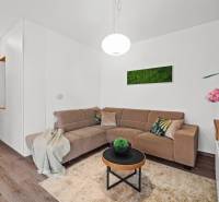 Living room with a couch, table, and wooden decor flooring in a 3-room apartment.