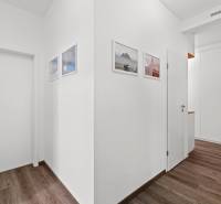 A corridor with white walls and a wooden decor floor, 3-room apartment.