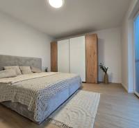 Bedroom in a 3-room apartment with a bed, wardrobe, and wooden decor flooring.