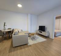 Living room of a 3-room apartment with a wooden decor floor, a sofa, and a dining table.