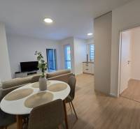 Dining area with a table and chairs, spacious living room, and floor with wooden decor.