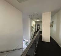 A hallway in offices with a staircase, decorated walls, and modern railing.