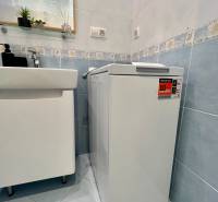 Bathroom with a washing machine and a sink in a 2-room apartment, blue tiles.