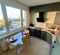 A kitchen in a 2-room apartment with a view, glass table, wooden floor decor.