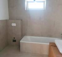 Bathroom in a family house with tiles and a bathtub.