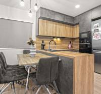 A kitchen corner with a wooden decor in a 3-room apartment with a stylish table and gray chairs.