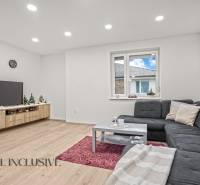 Living room with a corner sofa, wooden decor flooring, and a television in a three-room apartment.