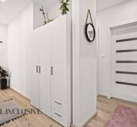 Hallway in a 3-room apartment with a white wardrobe, wood-patterned flooring, and green plants.
