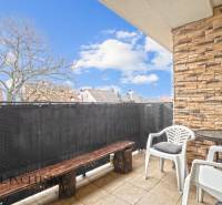 Balcony of a 3-room apartment in Vrakuňa with seating, brick cladding, and a view of the roofs.