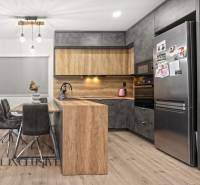 A kitchen in a 3-room apartment with a wooden decor floor, gray cabinets, and a dining table.