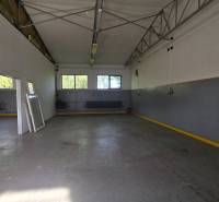 Interior of a warehouse with a metal structure, concrete floor, and windows.