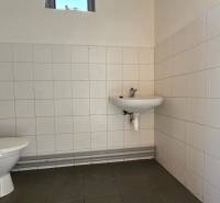 A restroom in warehouses and halls with white tiles and a small window.