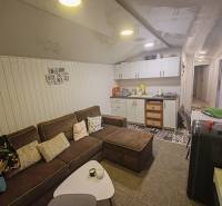 Living room in a cottage with a comfortable sofa, kitchen unit, and decorative wall cladding.