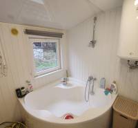 A bathroom in the cottage shows a bathtub, a boiler, and a small window with a view.