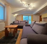 A bright living room in a holiday apartment with comfortable sofas and a wooden-patterned floor.