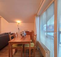 Dining table with five chairs and a lamp in a vacation apartment with wood-patterned flooring.
