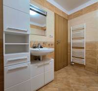 Bathroom in a holiday apartment with a sink, cabinet, and ladder radiator.