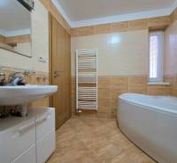 Bathroom in a recreational apartment with a bathtub, sink, and floor with a wooden decor.