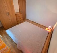 A bedroom in a holiday apartment with a bed and furniture on a wooden-decor floor.