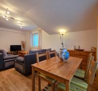 Living room in a holiday apartment with wood-patterned flooring, a sofa, and a dining table.