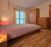 A bedroom in a holiday apartment with a wood-decor floor, a bed, and a wardrobe.