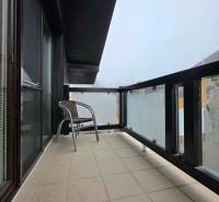 Balcony of a recreational apartment with a chair and glass railing.