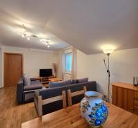 Living room in a holiday apartment with wood-patterned flooring and a decorative vase.