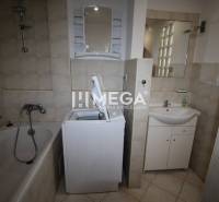Bathroom with a bathtub, washing machine, sink, and mirror in a 2-room apartment.