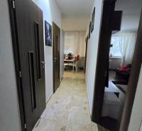 A hallway in a 3-room apartment with tiles and a view into the living room and kitchen.