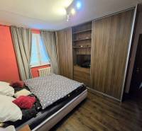 A bedroom in a 3-room apartment with a large wardrobe and a wooden decor floor.