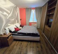 Bedroom with a bed, built-in wardrobes, and a wooden decor floor in a 3-room apartment.