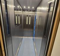 Illuminated interior of an elevator with metal walls and a blue floor.
