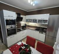 A kitchen in a 3-room apartment with white cabinets, stainless steel appliances, and decorations on the table.